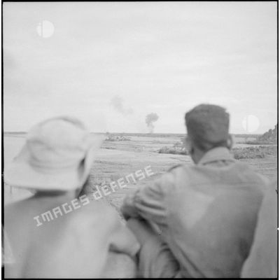 Vus de dos, deux tirailleurs du 1er RTA observant une colonne de fumée provoquée par le bombardement de Phong Du à 4,5 kms de Ninh Binh.