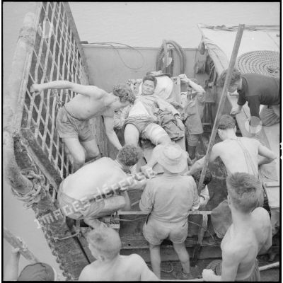 A l'aide de civières, les soldats évacuent des blessés viêt-minhs qu'ils transportent à bord du Landing Ship Support Large (LSSL).