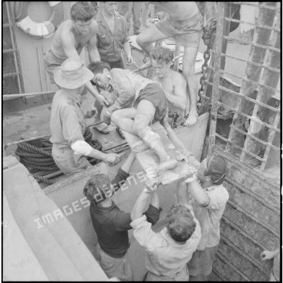 A l'aide de civières, les soldats évacuent des blessés viêt-minhs qu'ils transportent à bord du Landing Ship Support Large (LSSL).