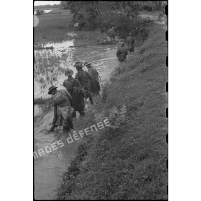 Soldats d'un RTA en progression dans l'eau, le long d'un talus.