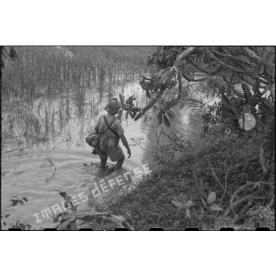 Soldats d'un RTA en progression dans l'eau, le long d'un talus.
