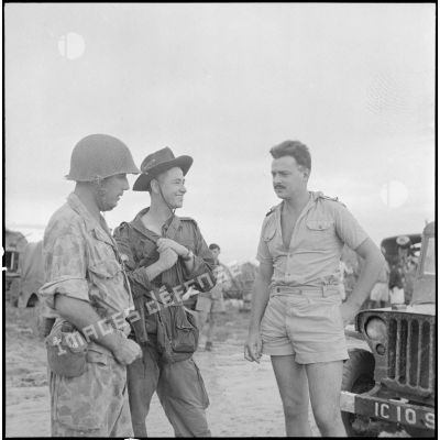 Trois soldats discutant près d'une jeep.