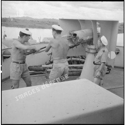A bord d'un LCI, des soldats chargent une pièce d'un canon de 75 mm.