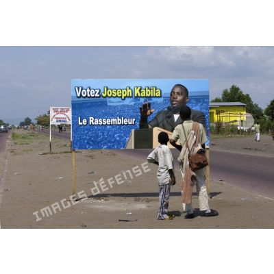 Sur la route menant au villagede N'Sele, la population devant les panneaux de campagne électorale.