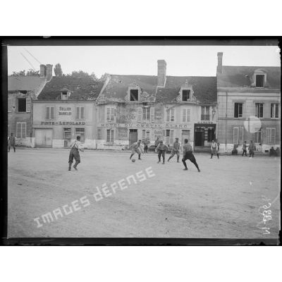 Des soldats participent à une partie de football dans les rues d'Hermonville. [légende d'origine]
