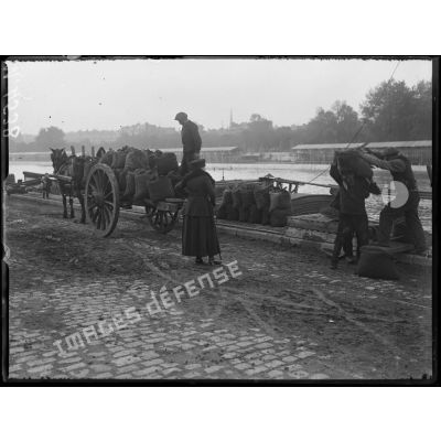 Paris, quai d'Orsay. Une dame surveille le déchargement de sa commande de charbon. [légende d'origine]