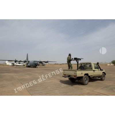 Un soldat malien sécurise le périmètre d'un avion-cargo Hercules C-130 H-30 de l'escadron de transport 2/61 Franche-Comté à bord de son pick-up sur l'aéroport de Bamako, au Mali.