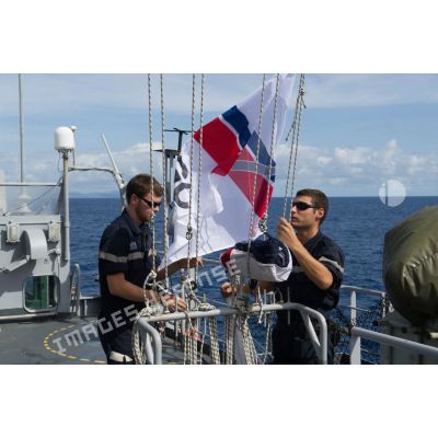 Un second maître et son équipier hissent le pavillon de garde-côte à bord de la frégate de surveillance Ventôse au large de la Martinique.