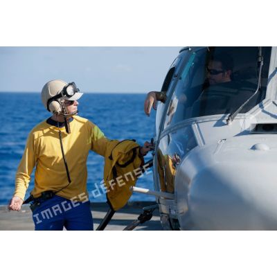 Un chien jaune discute avec le mécanicien d'un hélicoptère Panther AS-565 de la flottille 36F à bord de la régate de surveillance Ventôse, en mer des Caraïbes.