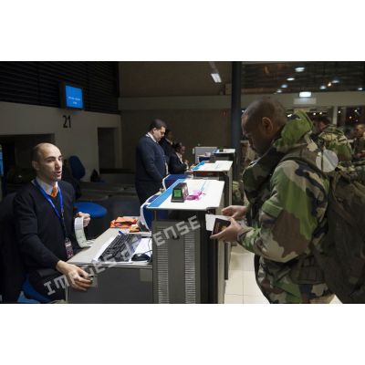 Un instructeur français enregistre ses bagages au guichet d'embarquement à l'aéroport de Roissy-Charles-de-Gaulle.