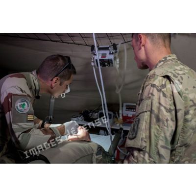 Un médecin des armées du SSA (Service de santé des armées) examine la bouche d'un artilleur français de la Task Force Wagram se plaignant de douleurs aux dents, en présence d'un aide soignant américain.