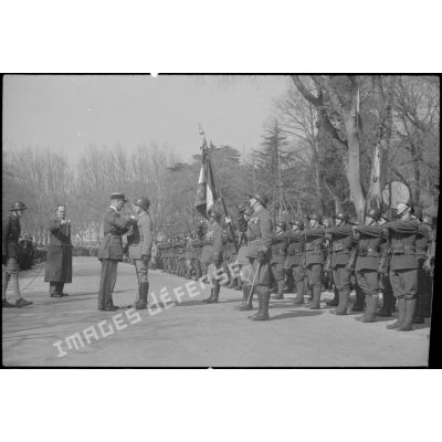 Au cours d'une cérémonie de remise d'emblèmes, le colonel commandant le 21e régiment d'infanterie coloniale (RIC) remet la Légion d'honneur à un capitaine, commandant de compagnie du régiment.