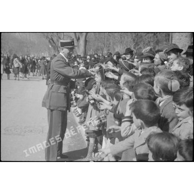 Le colonel, chef de corps du 21e régiment d'infanterie coloniale (RIC) quitte les lieux de la cérémonie de remise d'emblèmes en saluant les enfants des écoles présents.