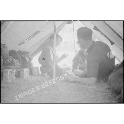 Des fantassins du 43e RIA discutent sous une tente dans le campement.