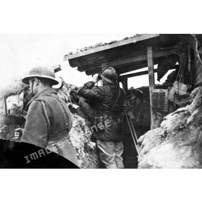 Sur le front dans une tranchée des soldats observent aux jumelles et aux binoculaires.