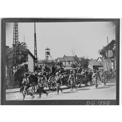 Des soldats britanniques de la BEF marchent en colonne dans une rue d'un village minier du département du Nord.