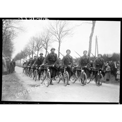 Photographié de face, un peloton de cyclistes polonais défile à pied bicyclette à la main.
