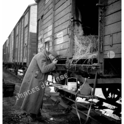Un soldat mange debout près d'un wagon.