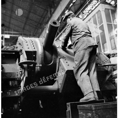 A l'atelier d'Issy-les-Moulineaux un ouvrier pose des rivets sur le masque du canon de 75 mm SA modèle 1935.