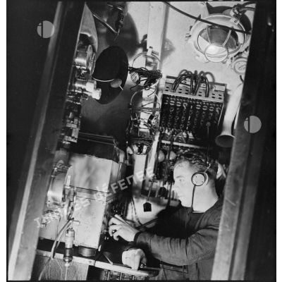 L'opérateur radio du sous-marin des FNFL (Forces navales françaises libres) la Minerve envoie ou réceptionne des messages depuis le poste central radio, au cours d'un exercice.