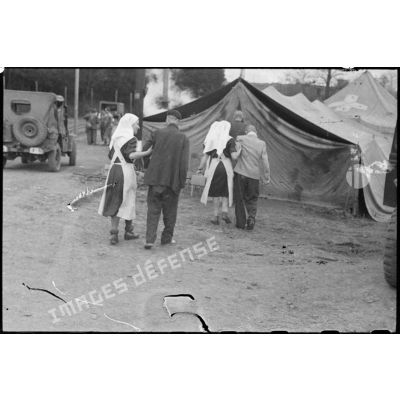Des déportés du camp de Vaihingen libéré sont soutenus par des infirmières jusqu'aux tentes sous lesquelles un bataillon médical va leur prodiguer les premiers soins.