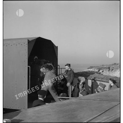 Lors de la visite de journalistes américains, des marins chargent un obus dans un canon de défense côtière dans la région de Brest.