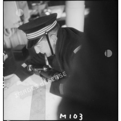 Un lieutenant de vaisseau, de quart à bord de l'aviso Amiral Mouchez au large de Dunkerque, consulte une carte.
