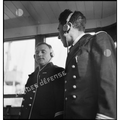 Portrait du lieutenant de vaisseau, commandant le patrouilleur La Lorientaise en compagnie d'un officier marinier, écouteurs sur les oreilles, à la passerelle de commandement.