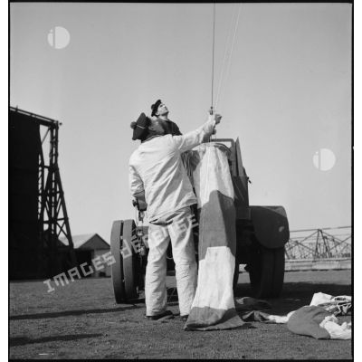 Des marins accrochent des manches à air au câble de retenue d'un ballon d'observation captif.