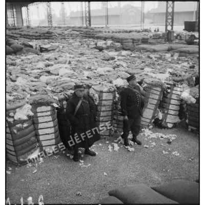 Douaniers montant la garde devant des stocks de denrées entreposées dans le port de Dunkerque, probablement saisies dans le cadre du blocus contre l'Allemagne.