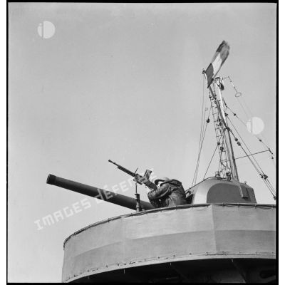 Servant d'un fusil-mitrailleurs FM 24/29 en position sur une des tourelles de canons de 100 mm à bord d'un torpilleur léger.