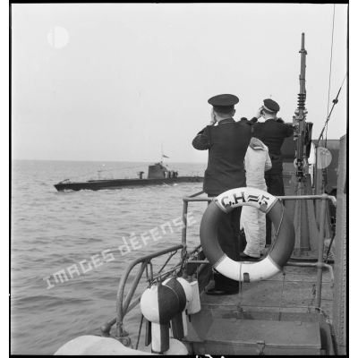 Un officier et un officier marinier, à bord du chasseur de sous-marins n°5, observent l'un d'entre eux naviguant sur leur bord.