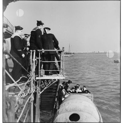Des marins permissionnaires quittent vraisemblablement le bord d'un ecorteur pour embarquer sur une chaloupe pour descendre à terre à Brest.