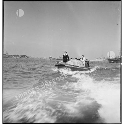 Des marins permissionnaires, vraisemblablement membres d'équipage d'un escorteur (classe T53), se rendent à terre à bord d'une chaloupe.