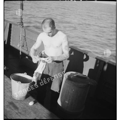 Un marin se rase sur le pont d'un chalutier réquisitionné par la Marine nationale comme dragueur de mines.
