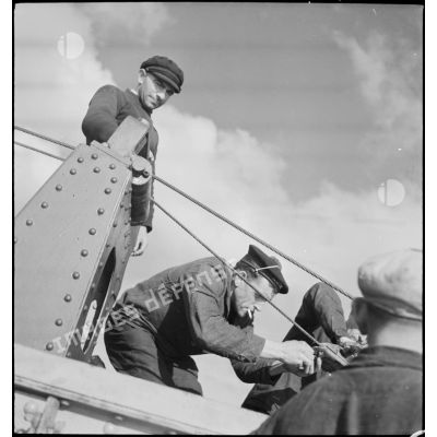 Un marin fixe les cisailles d'une drague à bord d'un chalutier réquisitionné par la Marine nationale pour servir de dragueur de mines.