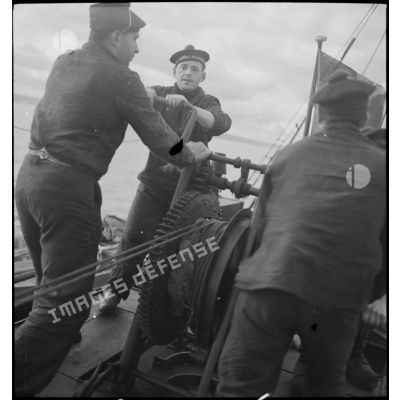Des marins halent la drague à bord d'un chalutier réquisitionné par la Marine nationale pour servir de dragueur de mines.