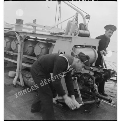 Des marins larguent des grenades sous-marines avec le grenadeur de sillage - à chaînes à maillons avec engrenage Galle - à bord du torpilleur léger Branlebas.