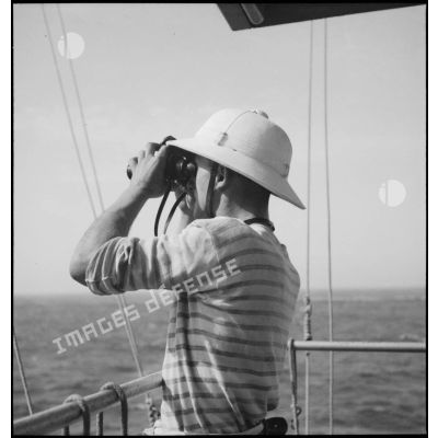 Un marin est de veille aux jumelles à bord du croiseur Strasbourg au large de l'Afrique occidentale française (AOF).