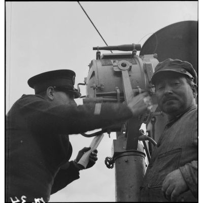 Un second maître utilise un projecteur à bord du chalutier de la marine marchande Roche noire, réquisitionné et armé par la Marine nationale comme dragueur de mines auxiliaire.