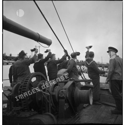 L'équipage d'un chalutier armé quittant le port de Brest salue la foule. A l'arrière plan, le pont tournant de Brest.