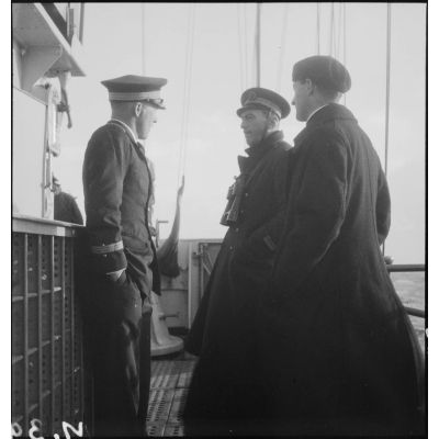 Officiers et aumônier en discussion sur la passerelle du contre-torpilleur Le Malin. A gauche, le lieutenant de vaisseau Jean Cornuault.