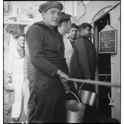 Matelots au ravitaillement à l'entrée des cuisines du contre-torpilleur Le Malin.