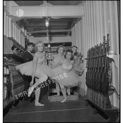 Des danseuses d'un corps de ballet traversent l'armurerie du porte-avions Béarn à bord duquel elles participent à un spectacle pour la soirée, la veille de Noël.