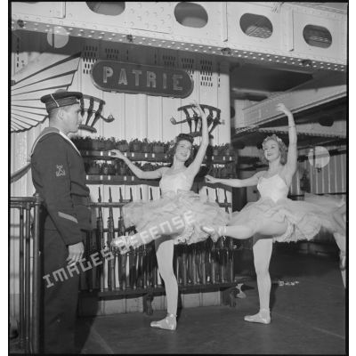 Des danseuses d'un corps de ballet font des exercices "à la barre" dans l'armurerie du porte-avions Béarn à bord duquel elles participent à un spectacle pour la soirée, la veille de Noël.