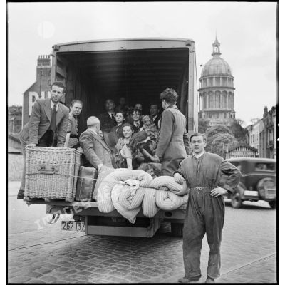 Plusieurs personnes d'origine belge ont pris place dans un camion pour fuir leur pays envahi par l'armée allemande. A l'arrière-plan, le dôme de la basilique Notre-Dame de Boulogne-sur-Mer.