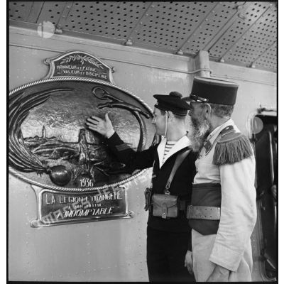 Un marin montre à un pionnier du 1er régiment étranger d'infanterie (REI) une plaque offerte par la Légion étrangère au contre-torpilleur L'Indomptable.