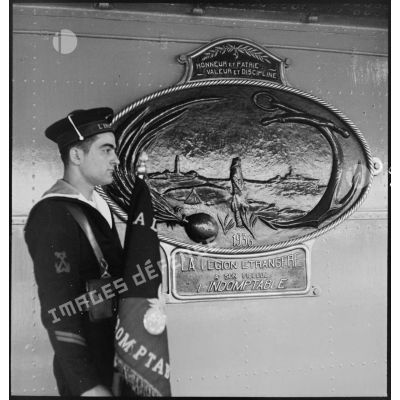 Le porte-fanion du contre-torpilleur L'Indomptable pose devant une plaque offerte par la Légion étrangère au navire.
