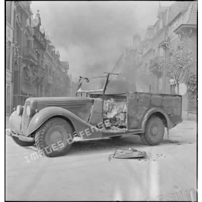 L'épave d'un véhicule militaire britannique (peut-être de marque Humber) brûle dans une rue de Malo-les-Bains suite à un bombardement de l'aviation allemande.