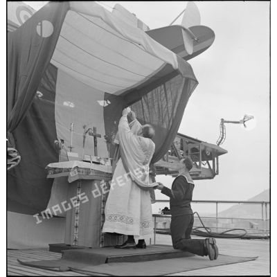 Elévation de l'hostie par l'aumônier du cuirassé Dunkerque au cours d'une messe célébrée à bord du navire.